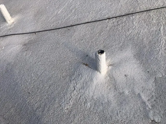 White TPO membrane roof surface showing puncture or penetration damage near a pipe boot