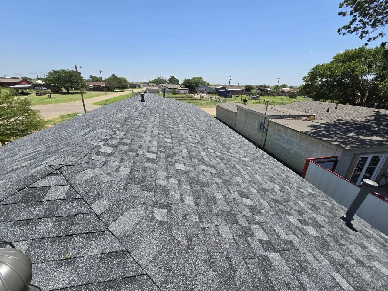 Wide-angle view of a completed gray dimensional shingle roof after storm damage restoration — 5 Star Roofing