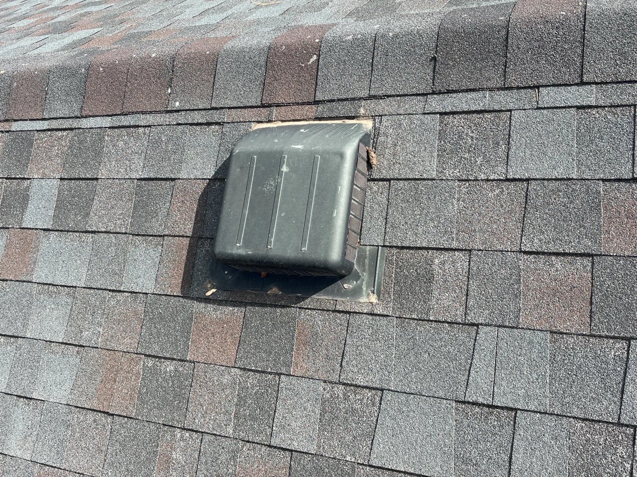 Roof vent installed on asphalt shingle roofing — detail of roofing hardware at slope transition