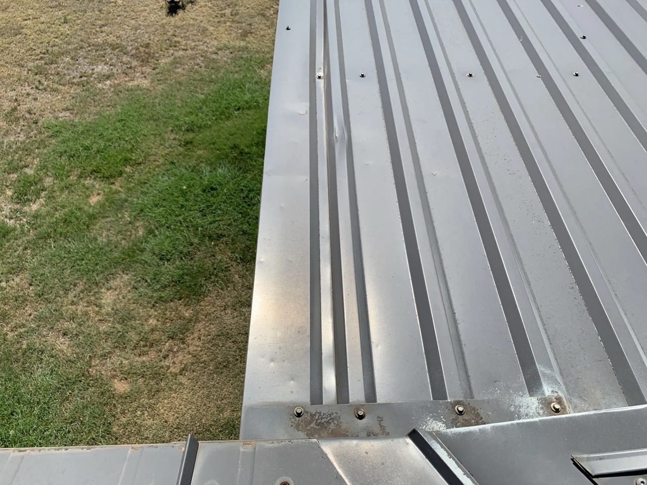 Close-up of gray standing seam metal roof panels on a residential home showing raised seams and edge trim — 5 Star Roofing