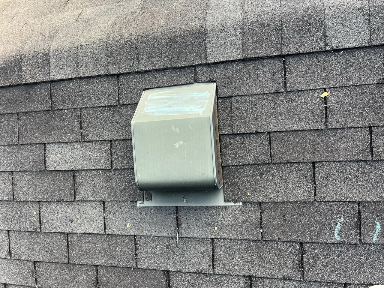 A box-style turtle roof vent installed on a gray asphalt shingle roof for attic ventilation