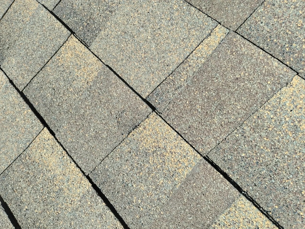 Close-up view of gray asphalt shingles showing the textured granule surface and layered construction