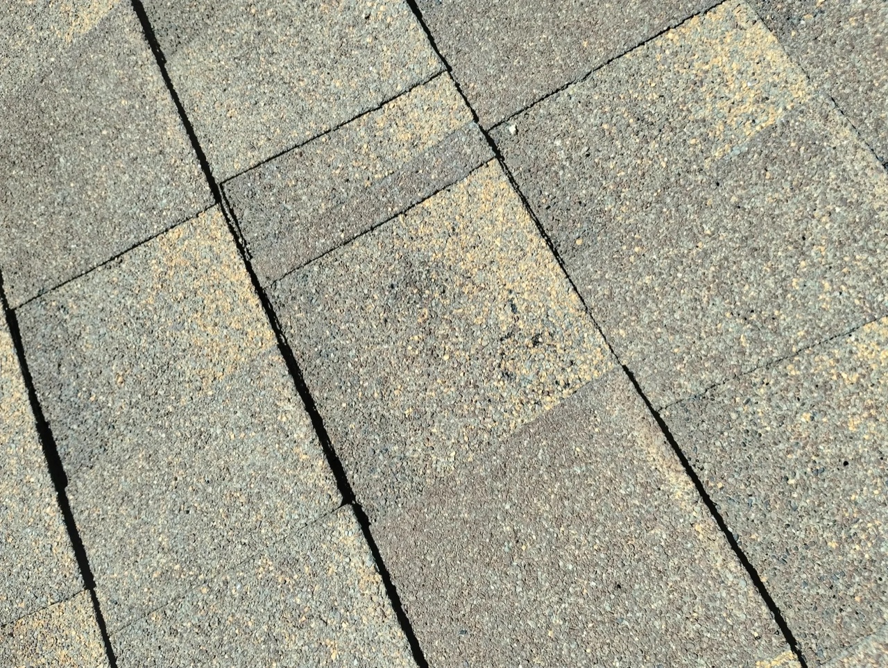 Close-up of dimensional asphalt shingles showing the layered profile that nails through into the sheathing below